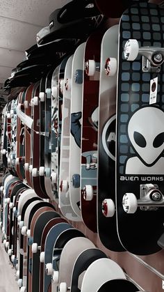 rows of skateboards with alien decals on them are lined up against the wall