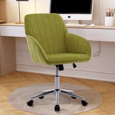 a green office chair sitting in front of a computer monitor on top of a desk