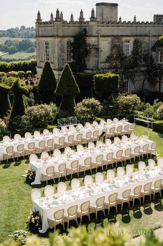 an outdoor wedding setup with tables and chairs set up in front of a castle like building