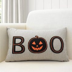 a striped pillow with a jack - o'- lantern on it sitting on a white couch