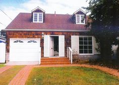 a brick house with white shutters and a red tiled walkway leading to the front door