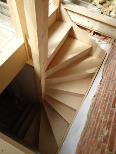 a spiral staircase is being built on the side of a brick wall in an unfinished room