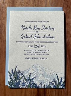 a wedding card with an image of a mountain and flowers on the front is shown