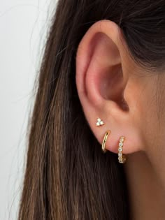 Small hoop earrings featuring eight tiny round bezel-set cubic zirconia gemstones. Understated and elegant, these dainty huggie hoops will mix and match effortlessly with other delicate earrings and are perfect for everyday wear. ∙ Sold individually (1 hoop) or by pair (2 hoops). * D E T A I L S * ∙ Material:  .925 Sterling Silver or  18K Gold Plated over .925 Sterling Silver  ∙ Dimensions: Outer diameter: 13mm // Inner diameter: 10mm  ∙ Stone: White Zirconia ∙ Hypoallergenic & nickel-free * P A C K A G I N G * ∙ All jewelry is sent out beautifully packaged in our signature box & ready for gifting. ∙ In order to reduce waste, we often put an order with multiple pieces in the same box. If one of the pieces is intended as a gift or if you would like each piece in its own box, just leave a no Second Piercing Earrings Gold, Third Earings Piercings, Ear With Three Piercings, Ear Piercing Three, Multiple Ear Piercings Aesthetic Gold, Three Love Piercing, Third Piercing Earrings, Ear Piercings Thirds, Three Ear Piercings Silver