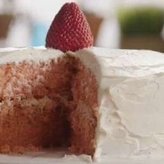 a cake with white frosting and a strawberry on top