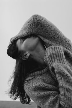 a woman with long hair wearing a sweater and looking up at the camera, in black and white