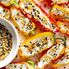 peppers stuffed with cheese and sprinkles next to a bowl of seasoning