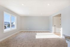 an empty living room with carpeted floors and large windows