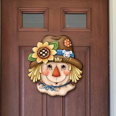 a wooden door with a scarecrow face and sunflowers on the top hat