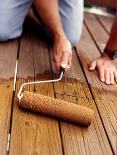 a man is painting a wooden floor with white paint and a roller on the ground