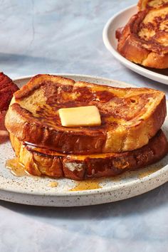 two plates with french toast and bacon on them, one has a piece of butter