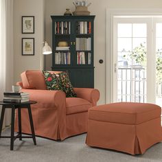 a living room with an orange chair and ottoman