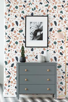 a dresser with a painting on the wall next to a lamp and a potted plant