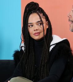 a close up of a person with long dreadlocks sitting in a chair and looking at the camera