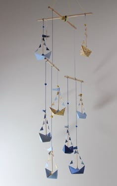 an origami mobile with paper boats hanging from it's sides and strings