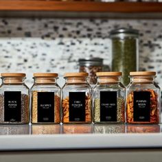 five glass jars filled with spices on top of a counter