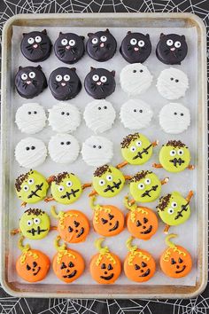 a tray filled with lots of decorated cookies on top of a spider web covered table