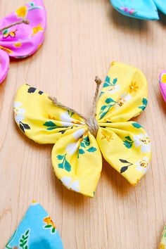 several different colored flowers on a wooden surface with one flower pinned to the back of it