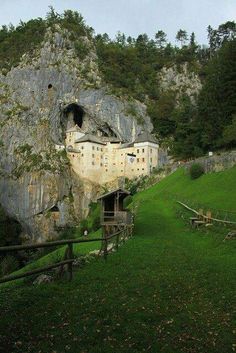 an old house built into the side of a mountain with a cave in it's center