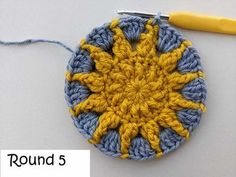 a crocheted circular with a yellow and blue flower on it next to a knitting needle