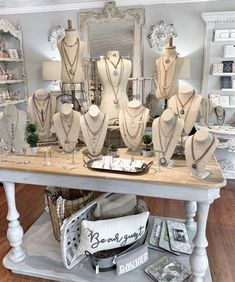 a table topped with lots of white mannequins and necklaces on display