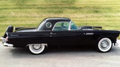 an old black car parked in a parking lot