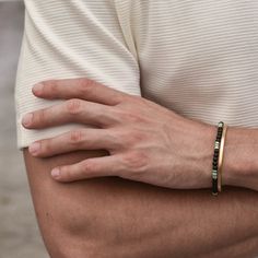 a close up of a person wearing a gold bracelet with a green bead on it