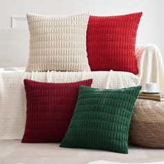 three pillows sitting on top of a white couch