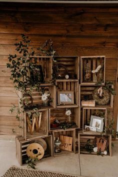 an arrangement of wooden crates with plants and pictures on them in front of a wall