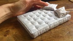 a person is holding a small mattress on a table