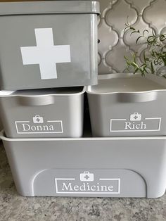 three grey containers with medical labels on them sitting on a counter top next to a plant