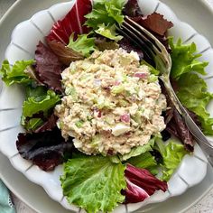 a white plate topped with salad next to a fork