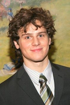 a young man in a suit and tie smiling at the camera with his name on it