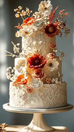 a white wedding cake with red and orange flowers