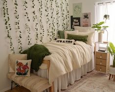 a bedroom with white walls and green plants on the wall behind the bedspread