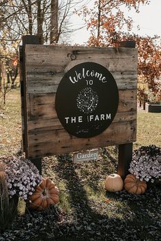 a welcome to the farm sign surrounded by flowers and pumpkins