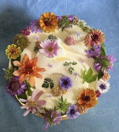 a cake decorated with flowers on top of a blue cloth covered tablecloth and white frosting