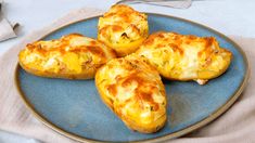 four cheesy potatoes on a blue plate with a napkin and utensils