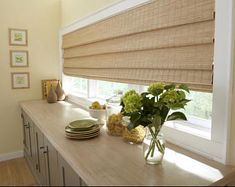 a kitchen counter topped with plates and vases filled with flowers next to a window