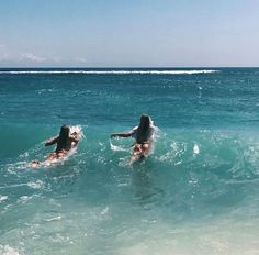 two women in the ocean on their surfboards