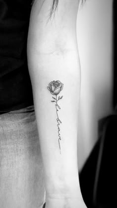 a black and white photo of a woman's arm with a rose tattoo on it