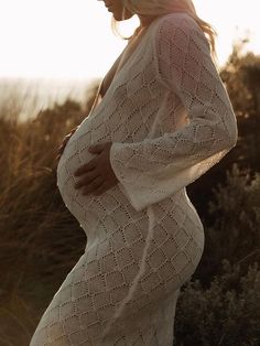 a pregnant woman in a white dress is posing for the camera with her hands on her stomach