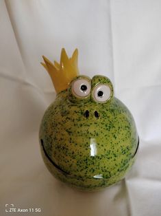 a ceramic frog with eyes and a crown on its head