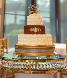 a three tiered wedding cake sitting on top of a glass table in front of a window