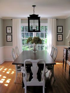 a dining room table with white chairs and a black chandelier