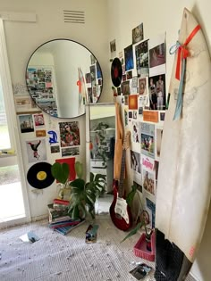 a surfboard leaning against a wall with pictures on it and a mirror above it