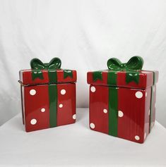 two red boxes with green bows and polka dots on them, one has a bow