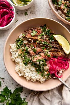 two bowls filled with rice, meat and veggies on top of a table