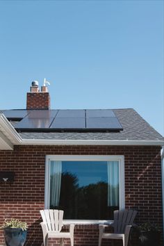 two chairs sitting on top of a brick patio next to a building with solar panels