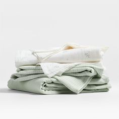 stack of folded cloths on top of each other in white and light green colors